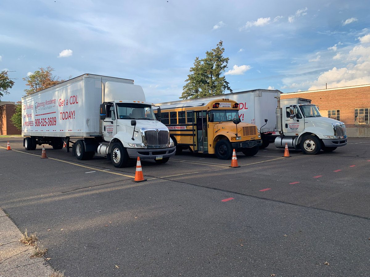 Two tractor-trailers and one school bus in practice yard