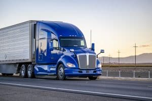Tractor-trailer with blue cab driving down road