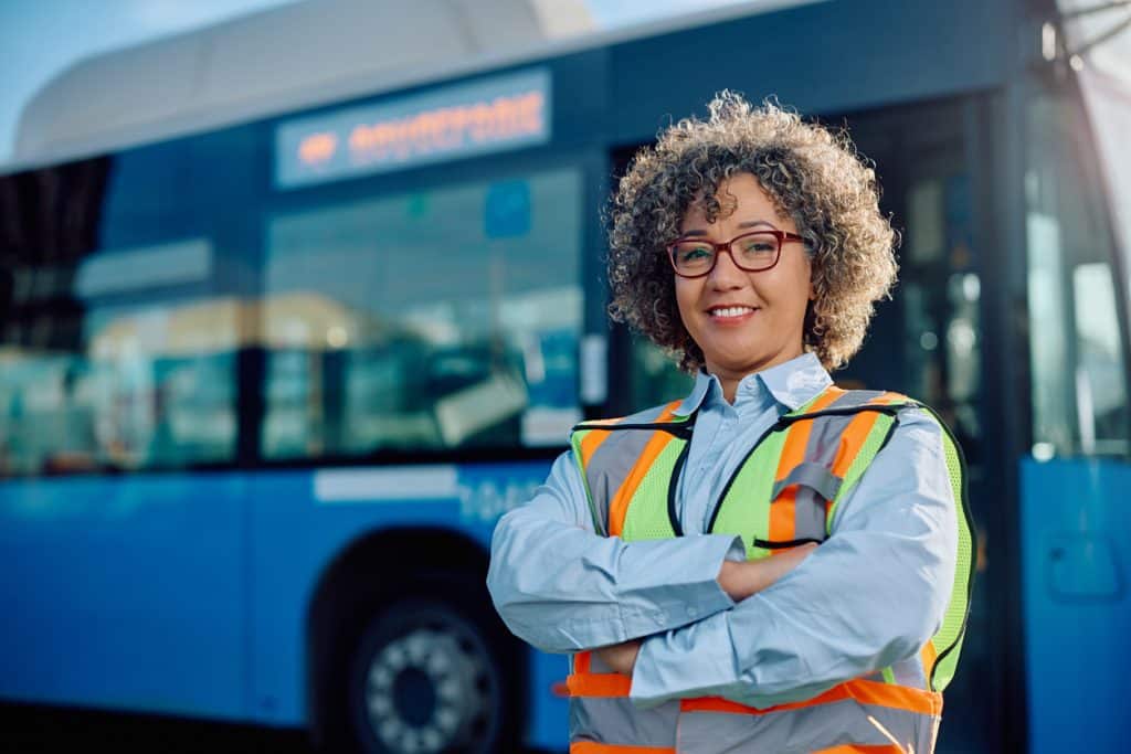 Bus driver smiling in front of bus
