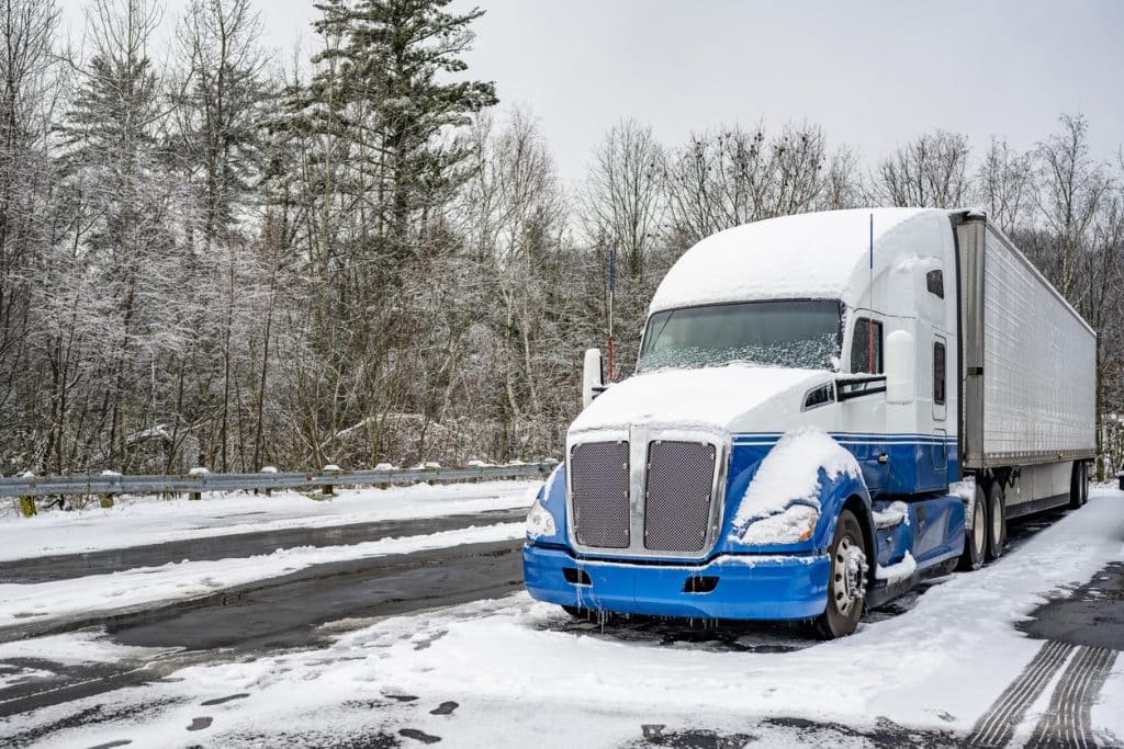 Tractor-trailer parked in parking lot and covered with snow