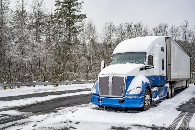 Tractor-trailer parked in parking lot and covered with snow