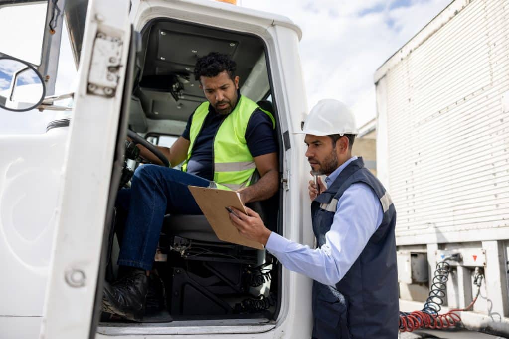 Truck driver and colleague looking at safety checklist