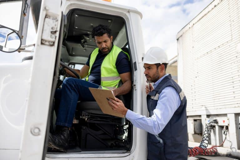 Truck driver and colleague looking at safety checklist