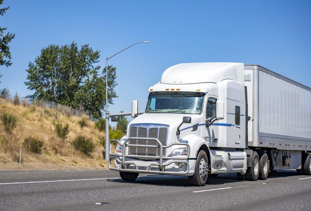 White tractor-trailer driving down road